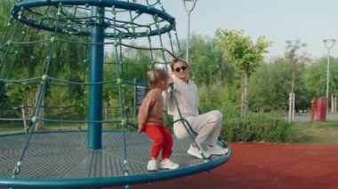 Genç mutlu anne ve bebek oyun parkında bir atlıkarıncada. Yüksek kalite 4k görüntü