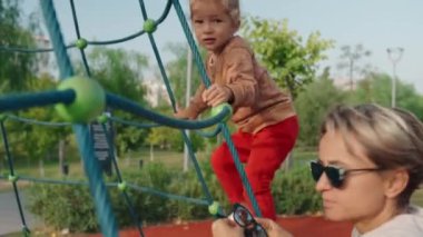 Genç mutlu anne ve bebek oyun parkında bir atlıkarıncada. Yüksek kalite 4k görüntü