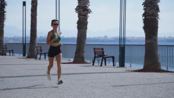 身材苗条的金发女子在人行道上慢跑 背景是城市建筑 活泼性感的女人跑着 日落时在室外锻炼 积极的生活方式 高质量的4K镜头 — 图库视频影像