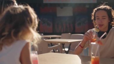 Üç çocuklu bir kadın tatil köyündeki barda taze meyve suyu ve kokteyl içiyor. Tüm kapsayıcı kavramlar. 