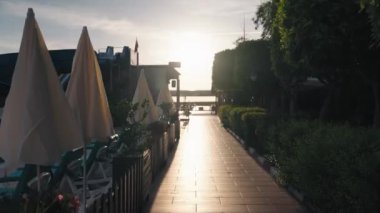 Okyanus kıyısındaki lüks otel havuzunda yüzen genç bir kadın. Neşeli kız gün doğumuyla buluşacak. Her şey dahil. Sabahın ve güneşin tadını çıkaran bir kız. Yüksek kalite 4k görüntü