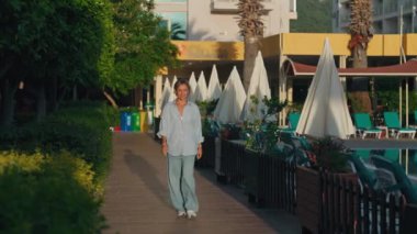 Okyanus kıyısındaki lüks otel havuzunda yüzen genç bir kadın. Neşeli kız gün doğumuyla buluşacak. Her şey dahil. Sabahın ve güneşin tadını çıkaran bir kız. Yüksek kalite 4k görüntü