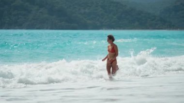 Yazın güneşli bir günde kumsalda atlayan sarı bikinili güzel bir kadın. Güneşli bir günde kumsalda zıplayan güzel bir kadının yan görüntüsü. Sıska kızın seksi sırtı, temiz.. 