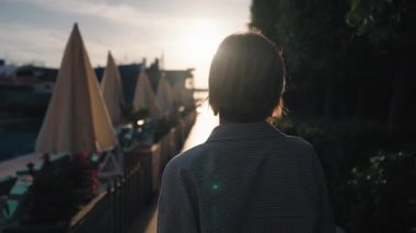 Okyanus kıyısındaki lüks otel havuzunda yüzen genç bir kadın. Neşeli kız gün doğumuyla buluşacak. Her şey dahil. Sabahın ve güneşin tadını çıkaran bir kız. Yüksek kalite 4k görüntü