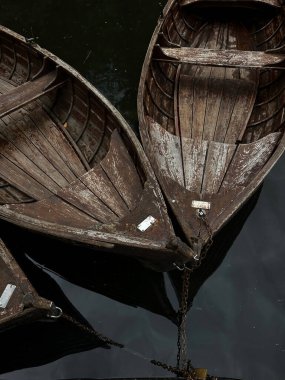 A collection of wooden boats tethered together on dark water, showcasing the rustic beauty and traditional craftsmanship of the vessels. clipart