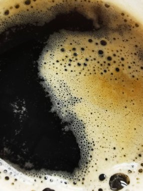 A close-up of a freshly brewed espresso, showcasing its rich, dark coffee and creamy golden foam. The contrast between the black coffee and light foam emphasizes the brew's quality, evoking warmth and comfort. clipart