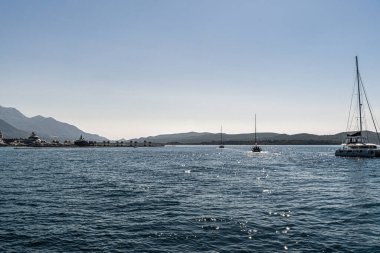 Yatlar ve yelkenliler, uzak tepeleri ve açık gökyüzü olan bir Akdeniz marinasında huzur içinde yüzerler. Lüks, yelkencilik, turizm, yaşam tarzı ve kıyı yaşamını göstermek için mükemmel..
