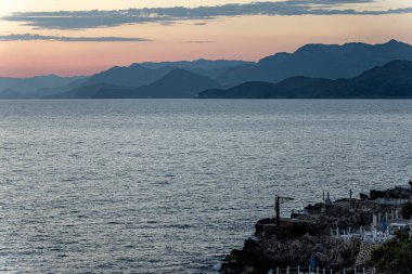 Adriyatik Denizi üzerinde renkli gün batımı ve Karadağ kıyı şeridinde katmanlı dağ siluetleri. Seyahat ilham kaynağı, doğa geçmişi ya da kıyı atmosferi temaları için mükemmel..