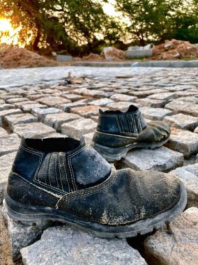 Gün batımında yolda terk edilmiş bir çift işçi botu.