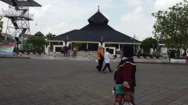 Demak, Endonezya - 01012022: Sepet taşıyan bir kadın belirgin bir çatıya sahip geleneksel bir camiye doğru yürüyor. Demak Camii.