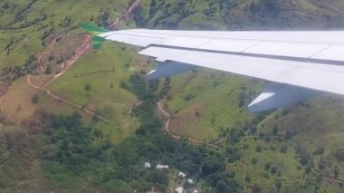 Komodo Havaalanı. Kalkış sırasında bir uçak penceresinden alınan yemyeşil tepelerin havadan görüntüsü..
