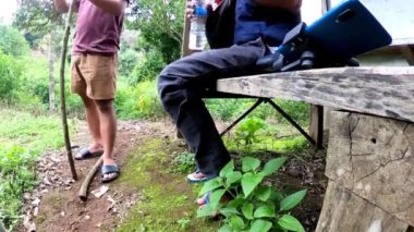 Bir adam plastik şişeden içiyor. Muria dağlarında yürüyüş, Orta Cava, Endonezya.