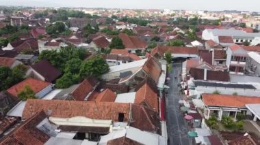 Kırmızı kiremitli çatıları ve dar sokakları olan, yeşillik ve arka planda bazı modern binalarla çevrili yoğun nüfuslu bir yerleşim bölgesinin havadan görünüşü. Menara Kudus.