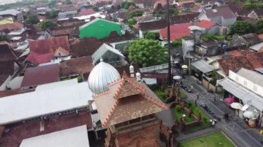 Beyaz kubbesi ve minaresi olan bir cami de dahil olmak üzere geleneksel ve modern binaların yoğun olduğu bir kasabanın havadan görünüşü. Menara Kudus.