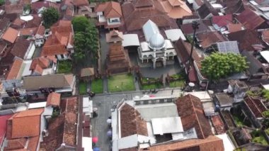 Geleneksel kırmızı çatılı binaları ve merkezinde beyaz kubbesi olan seçkin bir camii olan kalabalık bir kentsel alanın havadan görünüşü. Menara Kudus.