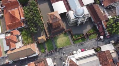 Kırmızı kiremitli çatıları, merkezi kulesi ve beyaz kubbesi olan tarihi bir tapınak kompleksi. Kompleks yeşillik ve yollarla çevrili, etrafta insanlar dolaşıyor. Menara Kudus.