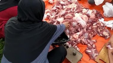 İnsanlar büyük bir tente üzerinde çiğ et ayırıp kesiyorlar..