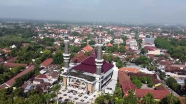 Bir çok evi ve yeşilliği olan bir yerleşim bölgesinde iki minaresi olan bir caminin havadan görünüşü. Jombang, Doğu Java, Endonezya.