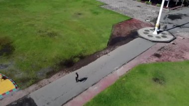 Bayrak direği ve kırmızı çatılı küçük bir binayla büyük bir çim tarlasının havadan görünüşü. Bölge bir parkın ya da umumi alanın parçası gibi görünüyor. Jombang, Doğu Java, Endonezya.