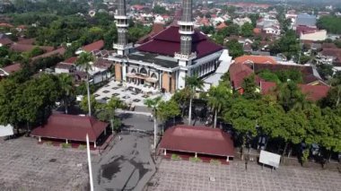 İki büyük minaresi olan, kentsel bir alanda ağaçlar ve binalarla çevrili büyük bir caminin havadan görünüşü. Jombang, Doğu Java, Endonezya.