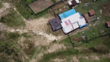 Kesongo çamur volkanı bölgesi, Blora, Endonezya. Kırsal alanda bir evin, toprak yolların ve çevreleyen yeşilliklerin havadan görüntüsü. Evde metal ve mavi branda çatısı karışımı bir şey var..