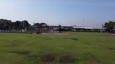 Çocuk parkı, yürüyüş yolları ve yeşil alanları olan bir parkın havadan görünüşü. Arka planda büyük bir bina ve bir otopark var. Jombang, Doğu Java, Endonezya.