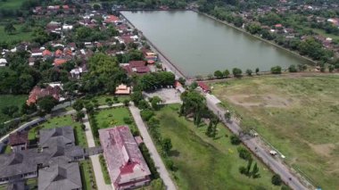 Endonezya, Mojokerto 'da Majapahit kraliyet havuzu. Büyük gölü ve yeşil tarlaları olan bir yerleşim bölgesinin havadan görüntüsü. Göletin etrafında evler ve binalar görülebilir..