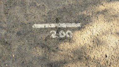 '200' yazan beyaz işaretli beton bir yüzeye yakından bakmak. Betonun dokusu görülebilir, küçük taşlar ve pürüzlü bir yüzeyi gösteriyor..