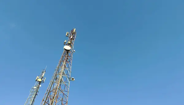 stock image Two tall communication towers against a clear blue sky.