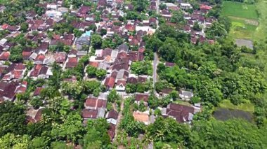 Pleret Arkeolojik Sitesi, Yogyakarta. Yeşillik ve tarım alanlarıyla çevrili geleneksel evleri olan yoğun nüfuslu bir yerleşim bölgesinin havadan görünüşü.