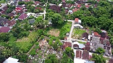 Kırmızı çatısı, yeşil bitkisi ve mezarlığı olan evlerin bulunduğu bir yerleşim yeri manzarası. Pleret Arkeoloji Bölgesi, Yogyakarta 'daki İslami Mataram Dönemi' nin Eski Camisi.