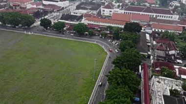 Yogyakarta şehrinde yollar ve binalarla çevrili büyük yeşil bir arazinin havadan görüntüsü. Yeşillik ağaçlar kenarlarda ve yolda birkaç araç görünüyor..