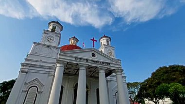 Semarang, Endonezya - 11022022: Beyaz sütunları ve kırmızı kubbesi olan tarihi bir kilise, eski şehrin tepesinde bir haç var. GPIB, Batı Endonezya 'daki Protestan Kilisesi' nin kısaltmasıdır..