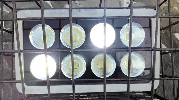 Şebeke benzeri bir yüzeye yerleştirilmiş, iki sıra halinde dizilmiş sekiz LED ışığın yukarıdan aşağı görüntüsü. Işıklar parlıyor, parlak yansımalar yaratıyor. Arkaplanda taş bir doku var..