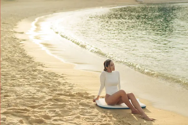 stock image Beautiful asian female surfer by the beach during sunset