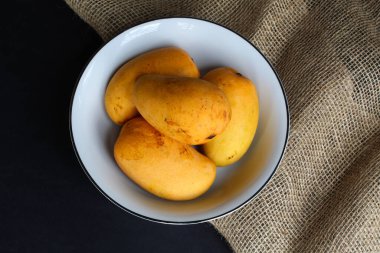 Koyu arkaplanda kumaşlı bir kase mango.