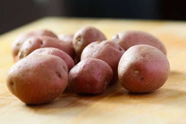 Tüm bebek kırmızı patatesler ahşap kesim tahtasının üzerinde.