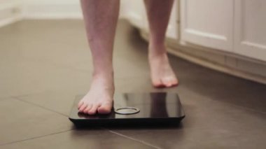 Banyo terazisinde duran beyaz bir erkek.