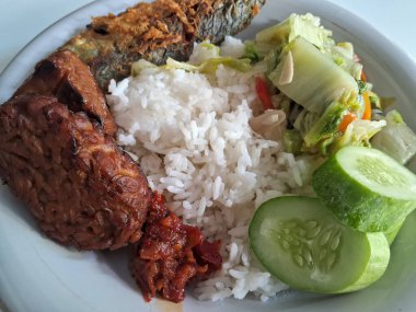 Endonezya geleneksel yemekleri. Pirinç, kızarmış balık, saut hardal yeşili ve tempe bacem..