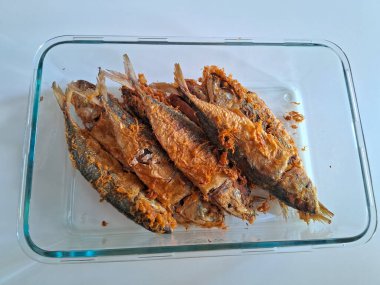 Baharat ve otlarla dolu bir kasede kızarmış balık.