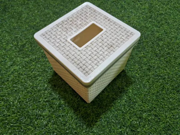 Yeşil yapay çimen arka planı olan beyaz bir doku kutusu.