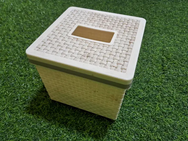 Yeşil yapay çimen arka planı olan beyaz bir doku kutusu.