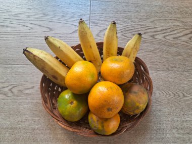 Ahşap bir arka planda, portakal ve muzlar.