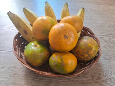 Ahşap bir arka planda, portakal ve muzlar.