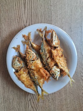 ahşap arka plan üzerinde beyaz bir tabak kızarmış balık