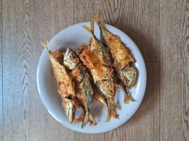 ahşap arka plan üzerinde beyaz bir tabak kızarmış balık