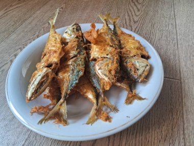 ahşap arka plan üzerinde beyaz bir tabak kızarmış balık