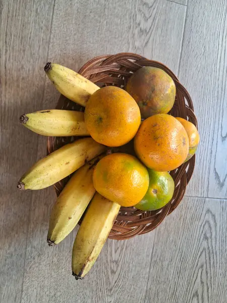 Ahşap bir arka planda, portakal ve muzlar.