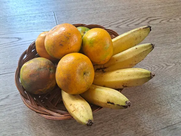 Ahşap bir arka planda, portakal ve muzlar.
