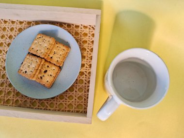 Basit ve cezbedici bir sahne, bir kupa su ve örülmüş bir tepside bir tabak kurabiye, rahatlatıcı bir mola için mükemmel.